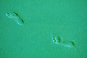 Pop art style mint green colored footprints on the sandy beach