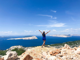Female traveler from behind enjoying view of islands and Adriatic sea of Croatia in summertime on road trip