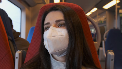 Pandemic, portrait of a European woman in a protective mask on a train. A woman in a protective mask rides the subway close-up.