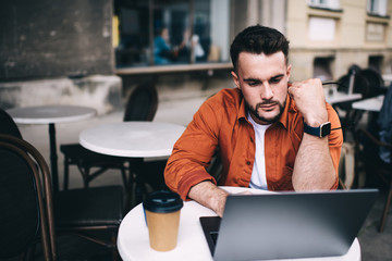 Male freelancer working on laptop while sitting in cafe