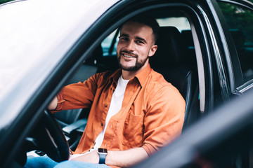 Cheerful male driver sitting in car