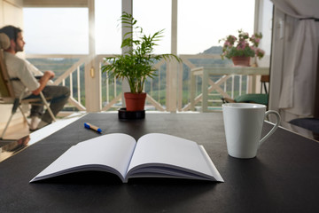  Black table with a cup, a plant and some books. A large background window.