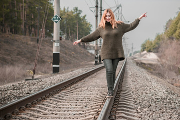 Fototapeta na wymiar Nice modern girl walking on rails, psychology of young woman, carelessness 