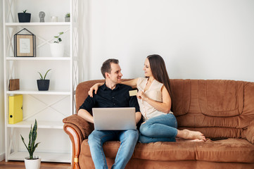 Young married couple on a sofa with a laptop