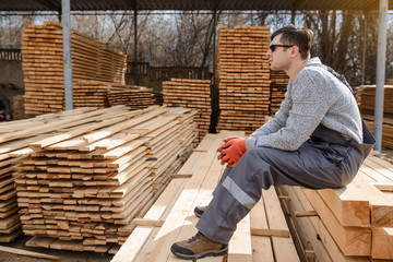 Portrait of young man carpenter at the wooden warehouse is resting