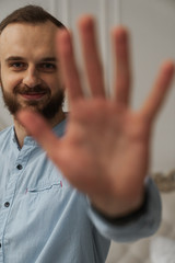 guy shows palm stop and smile, five fingers
