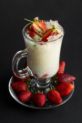 Traditional Turkish Ramadan Dessert;Gullac designed with fresh strawberries in Latte Coffee Cup on black background.