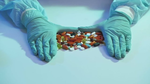 Coronavirus disease. Drug dosage. Doctor hands in protective gloves pushing up pill pile.