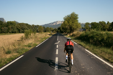 Female cyclist riding through narrow country road
