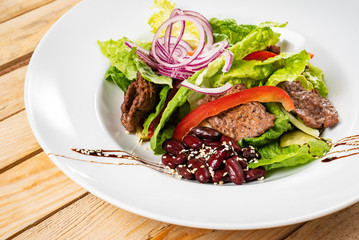 salad with beef, red beans and vegetables, wooden background