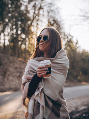 girl drinks coffee in a plaid in the sun