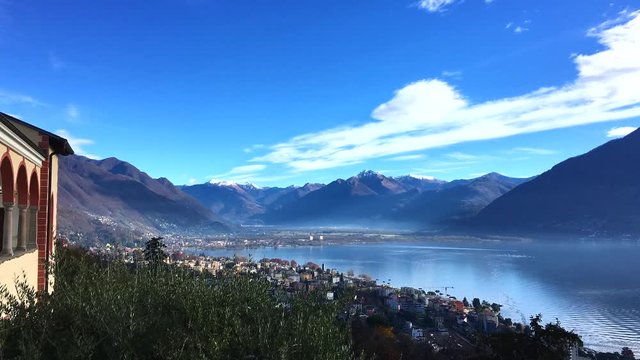 Stunning aerial panorama view of  Locarno cityscape and Lake Maggiore from Madonna del Sasso church, snow covered Swiss Alps mountain and blue sky cloud in background in autumn, Ticino, Switzerland