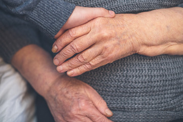 A young grandson takes care of, cares for and helps his grandmother of 90 years, holding her hand.