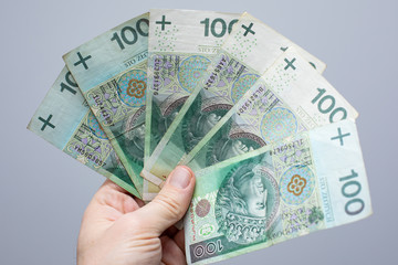 close up of one banknote with a face value of PLN 100 Polish money, zloty held  in the hands of a...