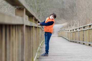Fototapeta na wymiar Portrait of a handsome boy standing on a wooden bridge.