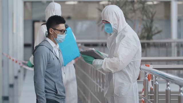Covid-19 temperature checkpoint. Doctor measures temperature of asian man in medical mask