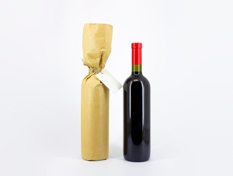Bottle of red wine in a brown paper. Vertical. Wine bottle mock-up isolated on soft gray background. Can be used for your design and branding. High resolution photo.