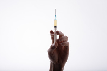 Close-up view of doctor holding syringe. White background. Hand with injection.