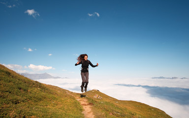 Fototapeta premium young woman jumping on the top of mountain