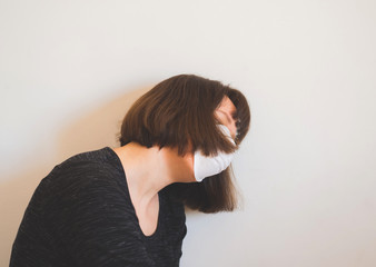 Fototapeta premium Frustrated caucasian young woman wearing face mask during Coronavirus pandemic quarantine staying home.
