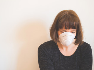 Frustrated caucasian young woman wearing face mask during Coronavirus pandemic quarantine staying home.