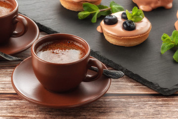 Cup of coffee on the table and a fruit basket on a serving board, fruit muffin with berries