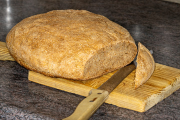 Sliced fresh home made bread with large bread knife on wooden cutting board