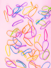 Fototapeta na wymiar Colorful rubber bands on pink paper background. Flat lay