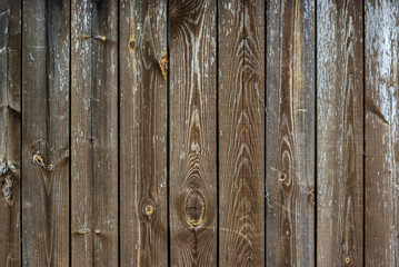 Shabby old grey-brown fence, abandoned and forgotten, a background of wooden planks, in the style of rustic, grunge, old fashion