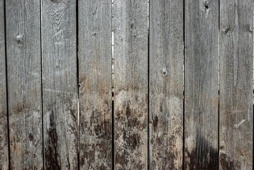 A very shabby old grey-brown fence, abandoned and forgotten, a background of wooden planks, in the style of rustic, grunge, old fashion