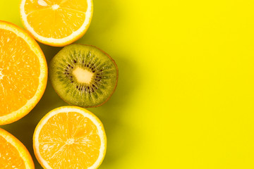 Fruit frame. Colorful fresh citrus fruits on a light green background. Orange, tangerine, lemon and kiwi are cut in half. Flat lay, top view, copy space.