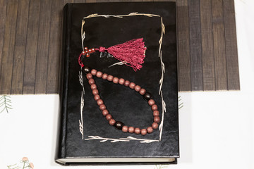 On the table is the book "Bible" in black binding. Above are the rosary.