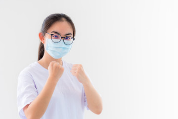 Portrait Asian young woman wear a mask to protect against Coronavirus, girl raise fists encourage to show fighting contagious disease concept stop virus Covid 19 outbreak to victor on white background