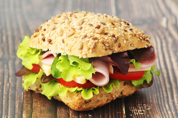 A sandwich with whole grain bread, ham and vegetables	