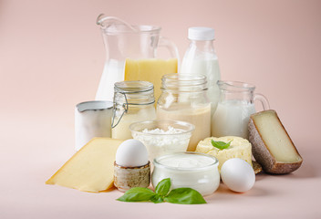 Fresh dairy products, milk, cottage cheese, eggs, yogurt, sour cream and butter on pink background