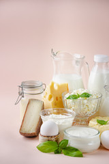 Fresh dairy products, milk, cottage cheese, eggs, yogurt, sour cream and butter on pink background