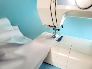 White fabric tucked into a sewing machine. Mockup or background for the overlaying a pattern on textile
