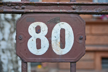 A house number plaque, showing the number eighty (80)