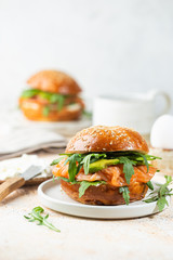 Burger sandwich with salmon, cream cheese, avocado and arugula on a light background, concept diet food, sandwich take away, healthy fast food