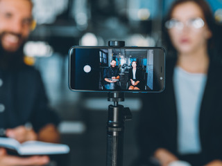 Business coaching. Management leadership. Partners recording video class with smartphone on tripod.