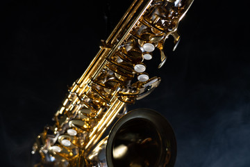 Obraz premium Golden shiny alto saxophone on black background with smoke. copy space