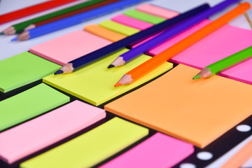 Colored pencils on a block of bright multicolored blank stickers