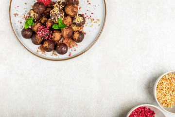 Various Homemade Raw Vegan Truffles or Energy Balls, such as Almond and Cacao, Dark Chocolate and Hazelnut Butter on Grey Plate and Light Background