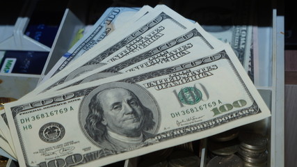 American dollars stacked on a dark background, in a wallet, in a cash drawer