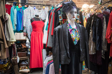 Spitalfields flea market. Mannequin in a cocktail dress and a hat with a veil on the background next to clothes