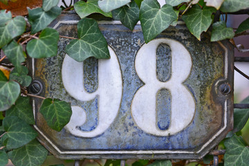 A house number plaque, showing the number ninety eight (98)