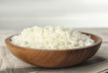 Wooden bowl with cooked rice on table, closeup