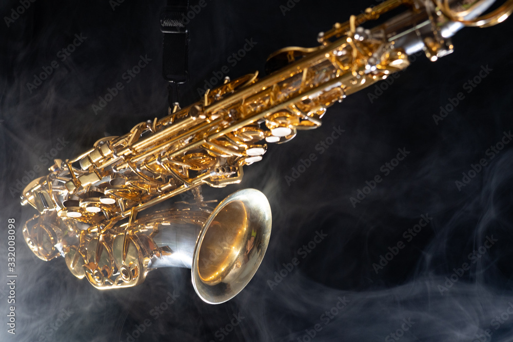 Wall mural Golden shiny alto saxophone on black background with smoke. copy space