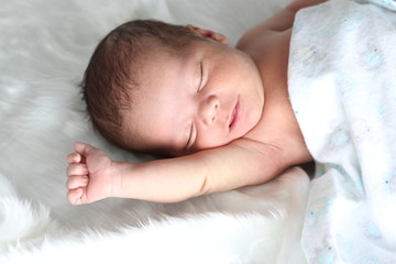 Bebé recién nacido dormido estirándose con manta blanca