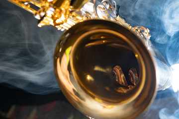 Golden shiny alto saxophone on black background with smoke. copy space